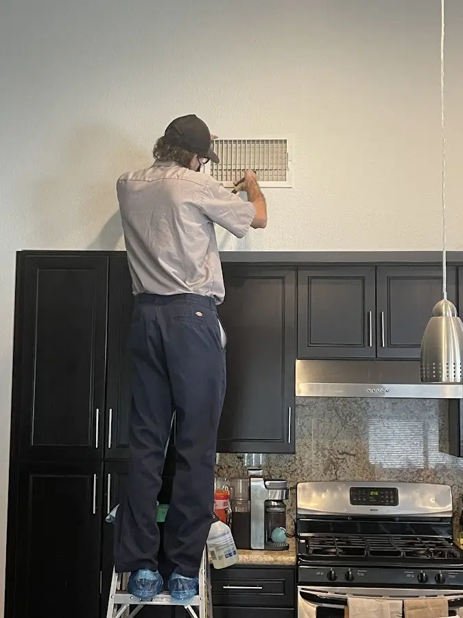 Technician inspecting an air vent during HVAC service in McKinney